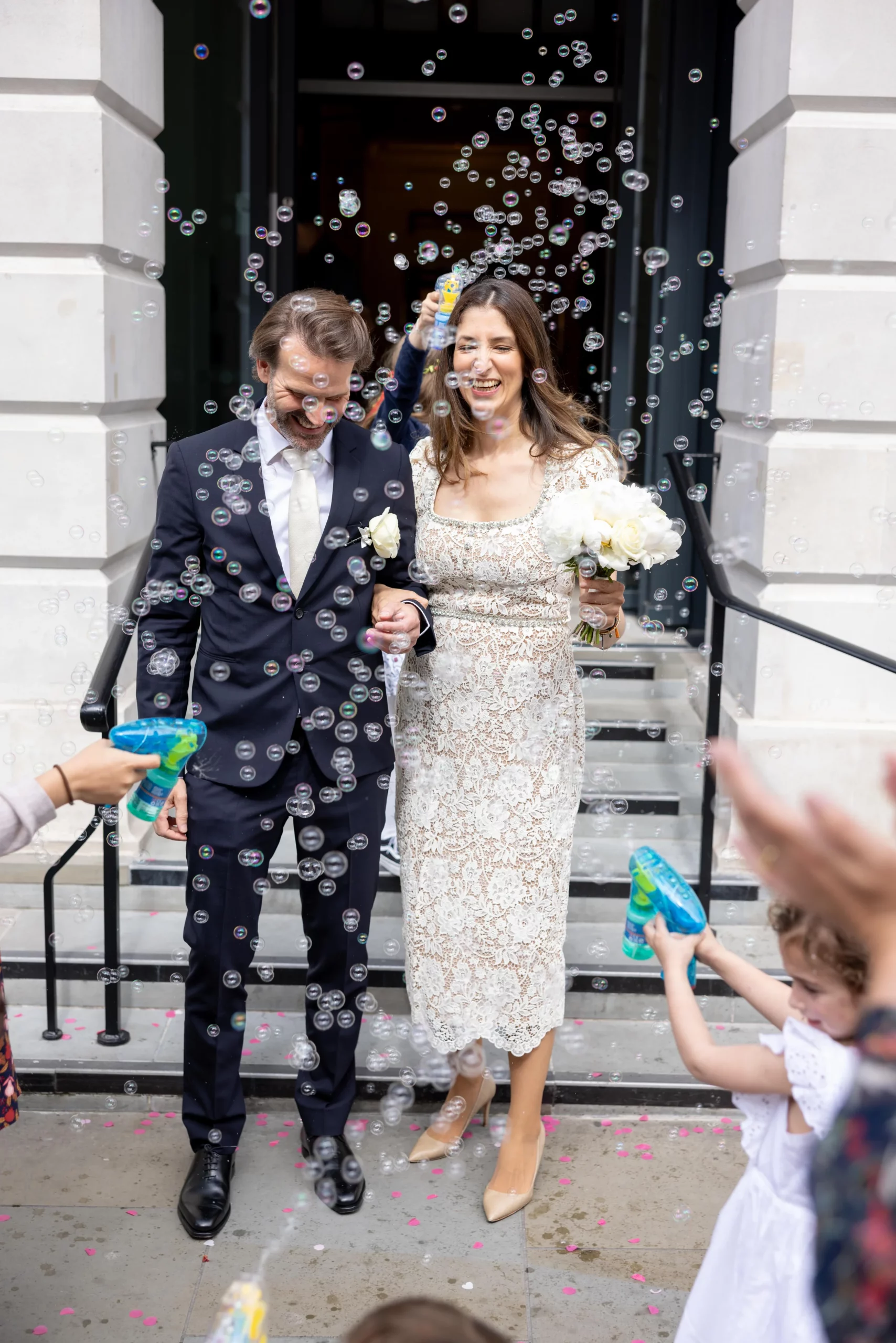 Couple leaving wedding surrounded by bubbles and confetti.