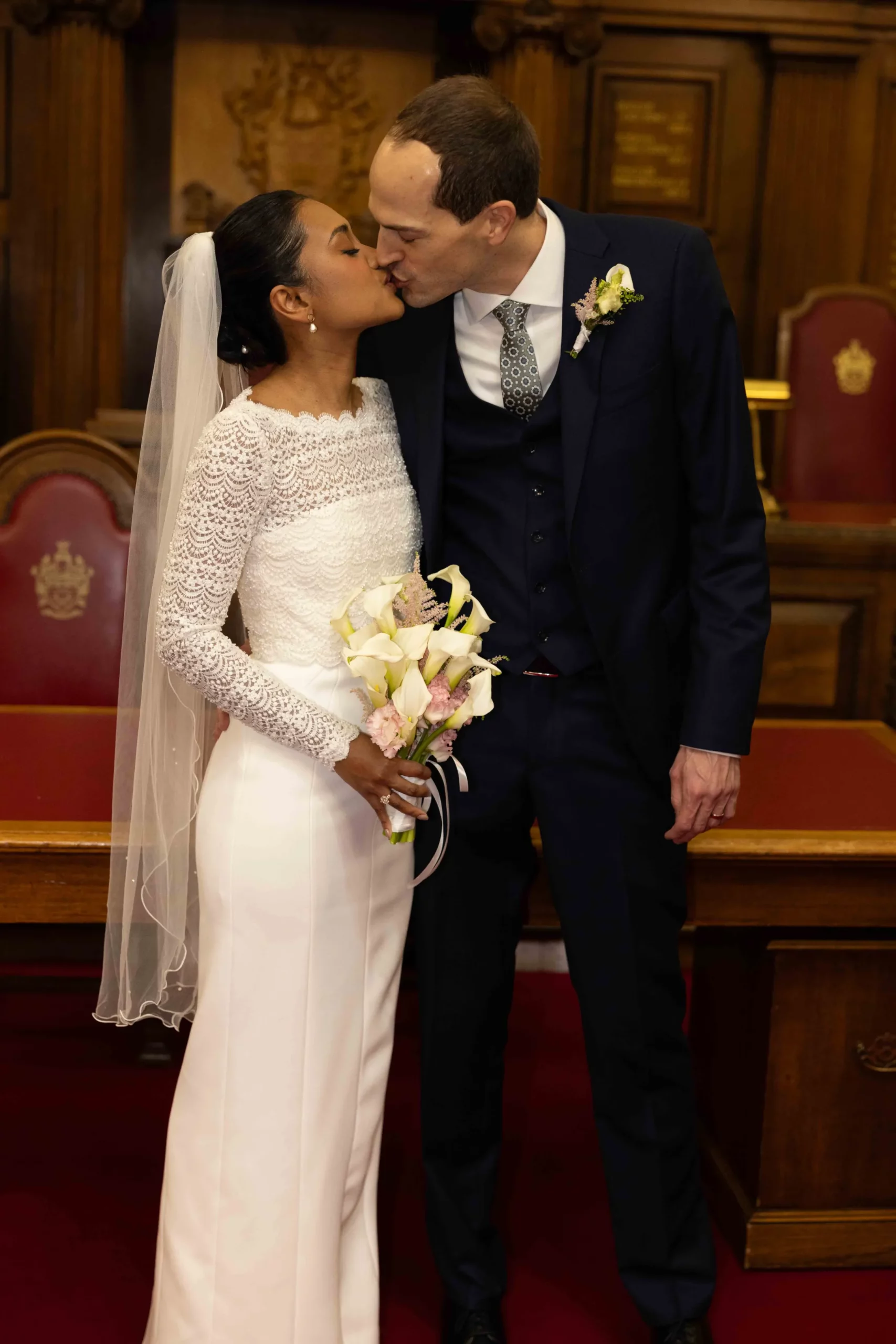 Bride and groom kissing during wedding ceremony indoors